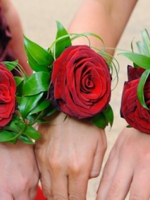 Three red roses worn on bridesmaids wrists.